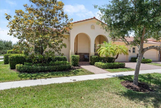 10145 SW Canossa Way, Port Saint Lucie, FL 34986 - mediterranean / spanish-style home with a garage, stucco siding, a front yard, decorative driveway, and a tiled roof