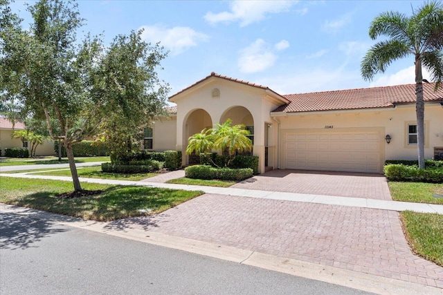 10145 SW Canossa Way, Port Saint Lucie, FL 34986 - mediterranean / spanish home featuring an attached garage, stucco siding, driveway, and a tile roof