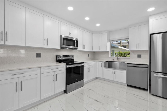 3040 Lake Shore Dr Unit 101, Riviera Beach, FL 33404 - kitchen featuring stainless steel appliances, a sink, light marble finish floors, white cabinets, and light countertops
