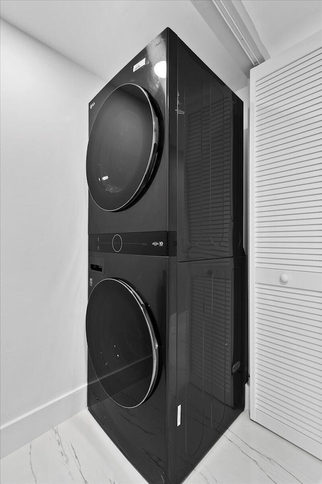 3040 Lake Shore Dr Unit 101, Riviera Beach, FL 33404 - washroom featuring stacked washer and clothes dryer, marble look tiles, and baseboards
