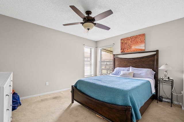 bedroom featuring baseboards, light carpet, a ceiling fan, and a textured ceiling