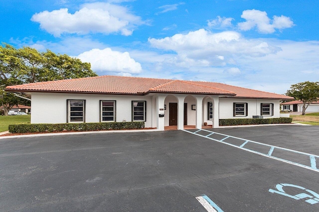 view of front of house featuring stucco siding, a tile roof, and uncovered parking
