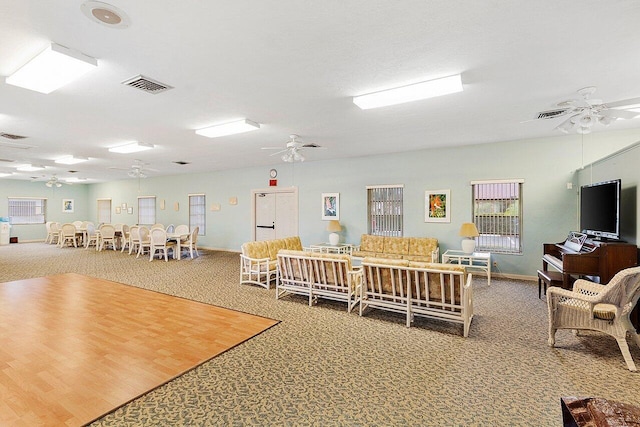 carpeted living area featuring ceiling fan, visible vents, and baseboards