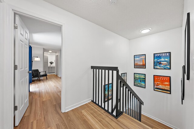 1420 Ocean Way Unit 30C, Jupiter, FL 33477 - corridor with an upstairs landing, light wood finished floors, baseboards, and a textured ceiling