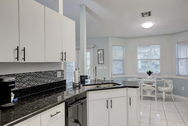 kitchen featuring a sink, dishwasher, dark stone counters, decorative backsplash, and visible vents