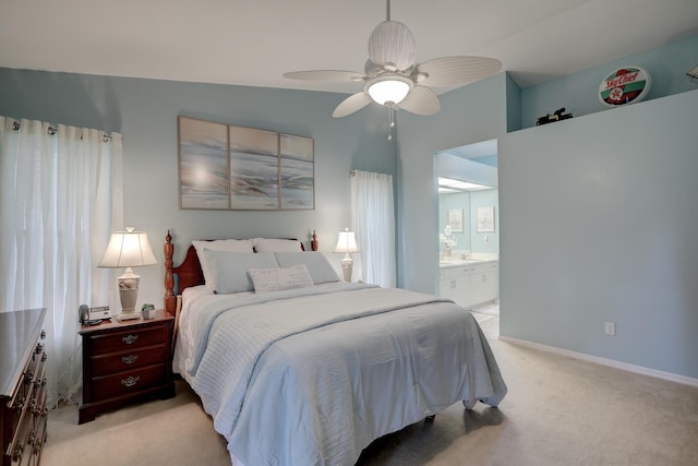 bedroom featuring light colored carpet, a ceiling fan, baseboards, and ensuite bathroom