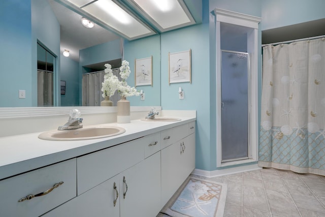 full bathroom with double vanity, baseboards, a sink, and a stall shower