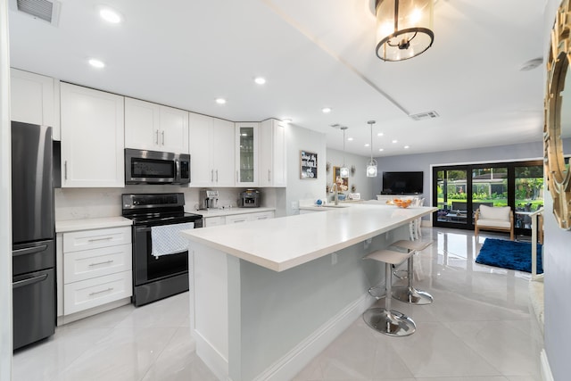 kitchen featuring stainless steel appliances, open floor plan, light countertops, glass insert cabinets, and a breakfast bar