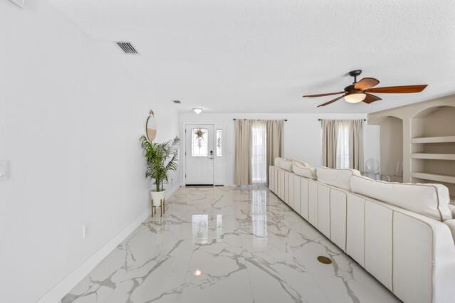 unfurnished living room with ceiling fan, visible vents, baseboards, and marble finish floor