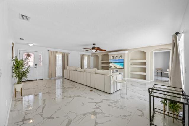 unfurnished living room featuring built in features, visible vents, a ceiling fan, and marble finish floor