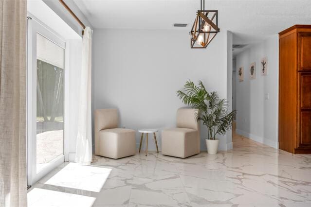 living area with visible vents, a chandelier, and marble finish floor