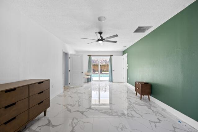 empty room featuring ceiling fan, marble finish floor, a textured ceiling, and visible vents