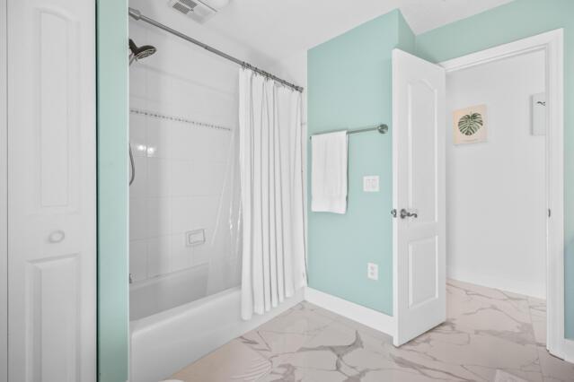bathroom featuring baseboards, visible vents, shower / bathtub combination with curtain, and marble finish floor