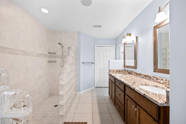 bathroom with double vanity, a walk in shower, a sink, and tile patterned flooring