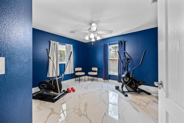 workout room with plenty of natural light, a ceiling fan, and marble finish floor