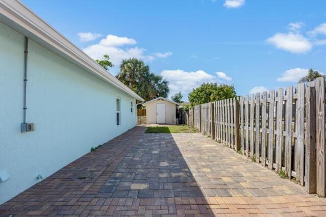 view of patio / terrace with a fenced backyard, an outdoor structure, and a shed