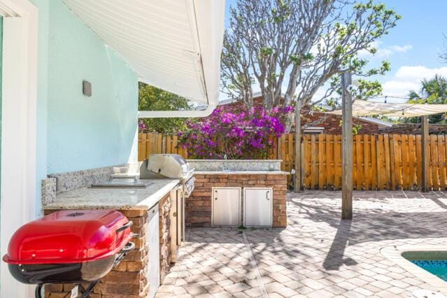 view of patio featuring area for grilling, fence, and a grill