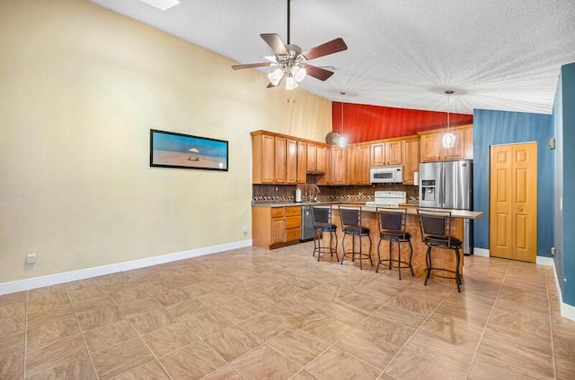 5578 Golden Eagle Cir Unit 5578, Palm Beach Gardens, FL 33418 - kitchen with a kitchen bar, a ceiling fan, baseboards, appliances with stainless steel finishes, and a kitchen island