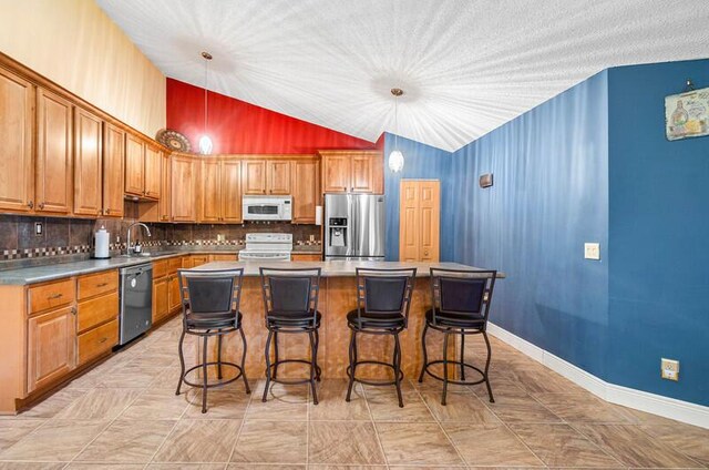 5578 Golden Eagle Cir Unit 5578, Palm Beach Gardens, FL 33418 - kitchen featuring a center island, a sink, backsplash, appliances with stainless steel finishes, and lofted ceiling