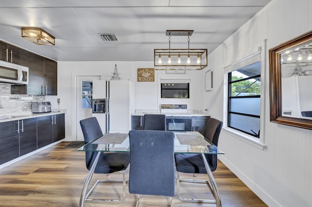 dining area featuring visible vents, baseboards, and wood finished floors
