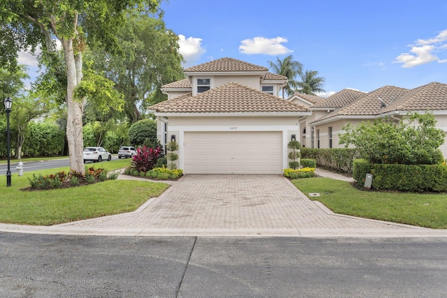 mediterranean / spanish-style home with stucco siding, a garage, driveway, and a front lawn