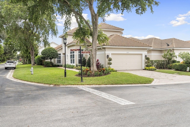 mediterranean / spanish home with a garage, a front lawn, stucco siding, and a tiled roof