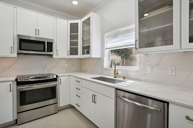 kitchen featuring appliances with stainless steel finishes, tasteful backsplash, light stone countertops, a sink, and white cabinetry