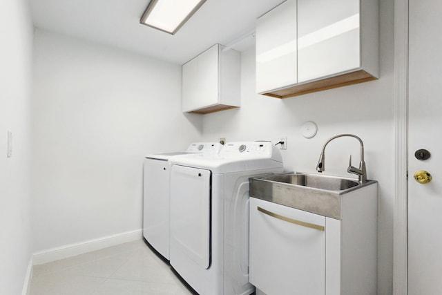 clothes washing area featuring cabinet space, a sink, baseboards, light tile patterned flooring, and washer and clothes dryer