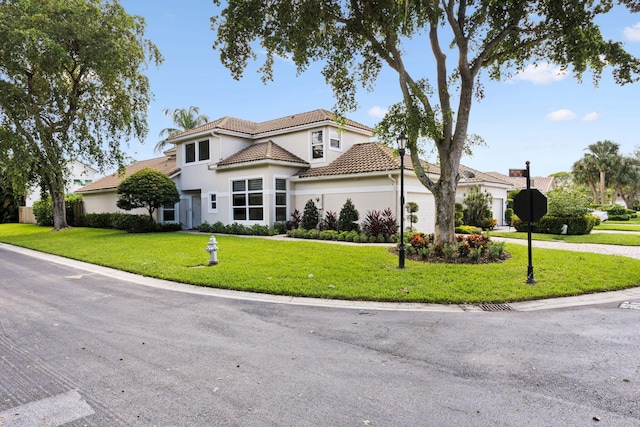 view of front of property featuring driveway, a tile roof, a front yard, a garage, and stucco siding
