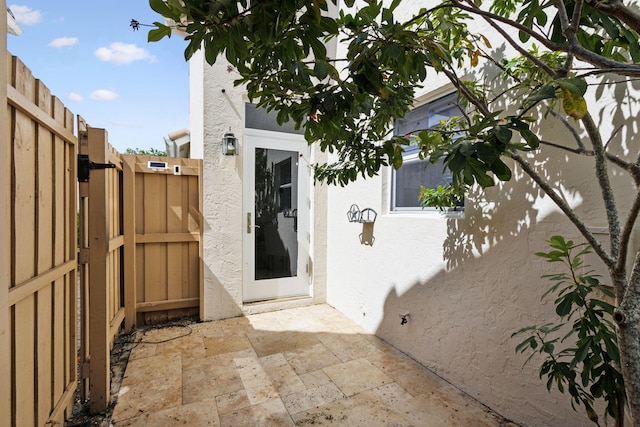 entrance to property with a patio, fence, a gate, and stucco siding
