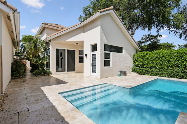 back of property featuring a patio, a fenced in pool, a tile roof, and stucco siding
