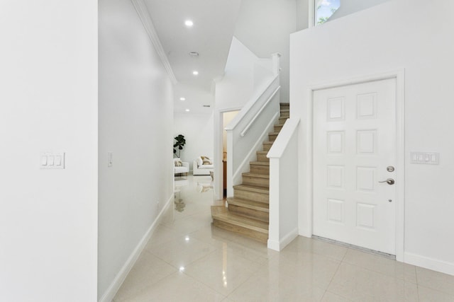 foyer with stairway, tile patterned floors, baseboards, and ornamental molding