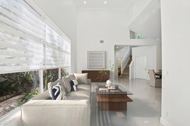 living room with visible vents, ornamental molding, stairs, a towering ceiling, and tile patterned floors