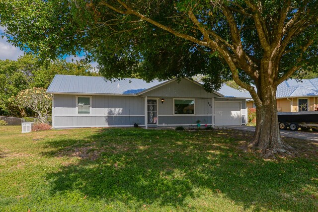 single story home featuring a garage, driveway, a front yard, and metal roof
