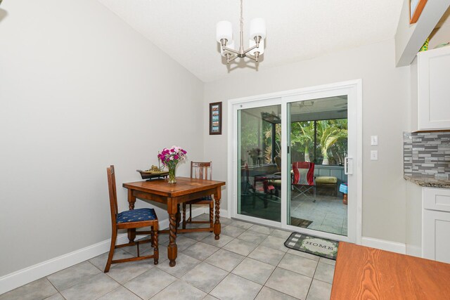 dining space featuring baseboards, an inviting chandelier, light tile patterned floors, and lofted ceiling