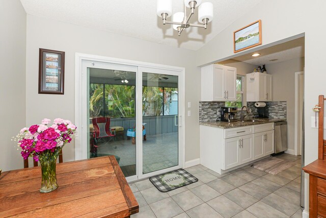 entryway featuring a chandelier, light tile patterned floors, baseboards, a sink, and lofted ceiling