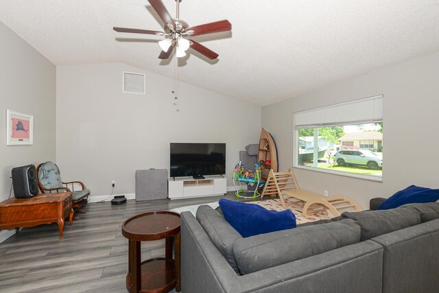 living area featuring visible vents, wood finished floors, baseboards, ceiling fan, and vaulted ceiling