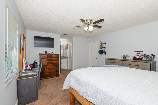 carpeted bedroom featuring visible vents, connected bathroom, a textured ceiling, and ceiling fan