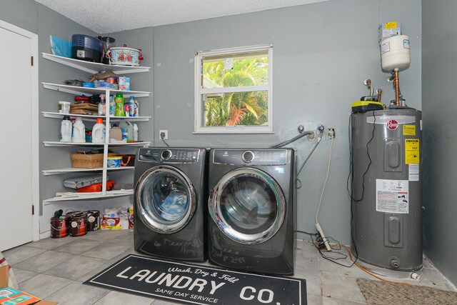 washroom featuring washer and dryer, laundry area, a textured ceiling, tile patterned floors, and water heater