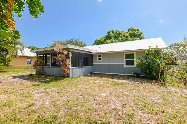 back of property with a sunroom, fence, a yard, and metal roof