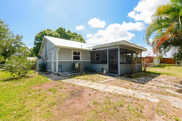 rear view of property with fence, a sunroom, and central AC