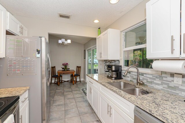 kitchen featuring a sink, white cabinets, backsplash, and visible vents