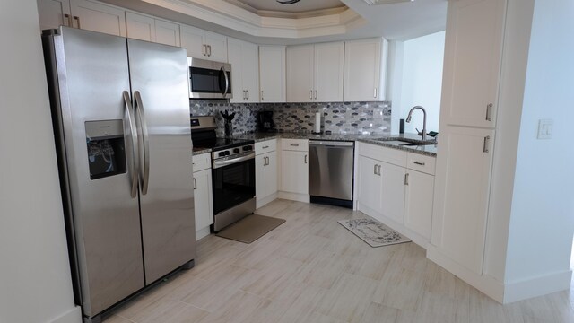 9500 S Ocean Dr Unit 1502, Jensen Beach, FL 34957 - kitchen featuring appliances with stainless steel finishes, a sink, dark stone counters, a tray ceiling, and decorative backsplash
