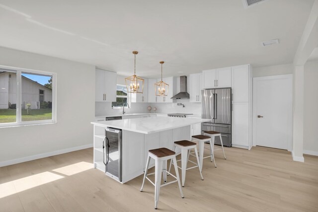 4372 SW Bimini Cir N, Palm City, FL 34990 - kitchen featuring high end fridge, wall chimney range hood, wine cooler, light wood-style floors, and baseboards