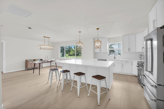 4372 SW Bimini Cir N, Palm City, FL 34990 - kitchen with stainless steel appliances, a sink, light wood-style floors, light countertops, and a breakfast bar