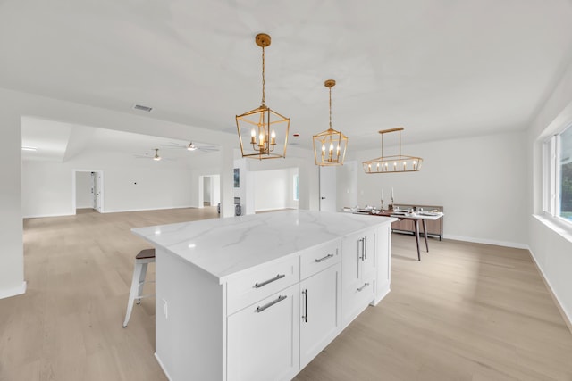 4372 SW Bimini Cir N, Palm City, FL 34990 - kitchen featuring light wood-style floors, a center island, light stone countertops, and white cabinetry