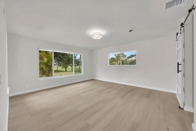 4372 SW Bimini Cir N, Palm City, FL 34990 - unfurnished room featuring a barn door, light wood-type flooring, and baseboards