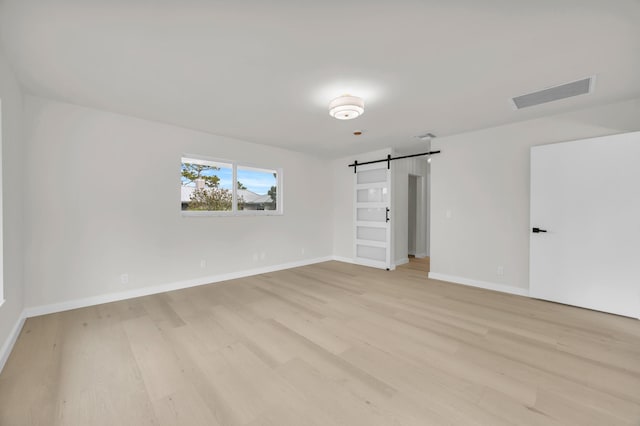 4372 SW Bimini Cir N, Palm City, FL 34990 - unfurnished bedroom featuring a barn door, light wood finished floors, and baseboards