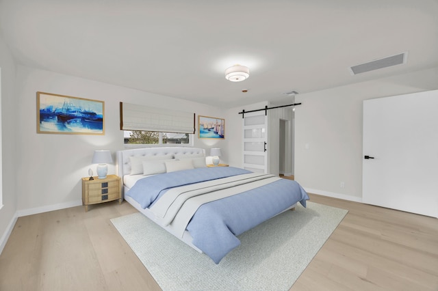 4372 SW Bimini Cir N, Palm City, FL 34990 - bedroom featuring a barn door, light wood finished floors, and baseboards