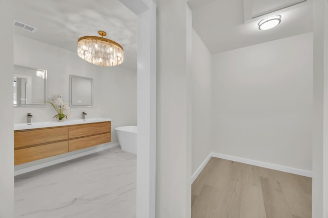 4372 SW Bimini Cir N, Palm City, FL 34990 - bathroom with double vanity, a freestanding bath, baseboards, and a chandelier